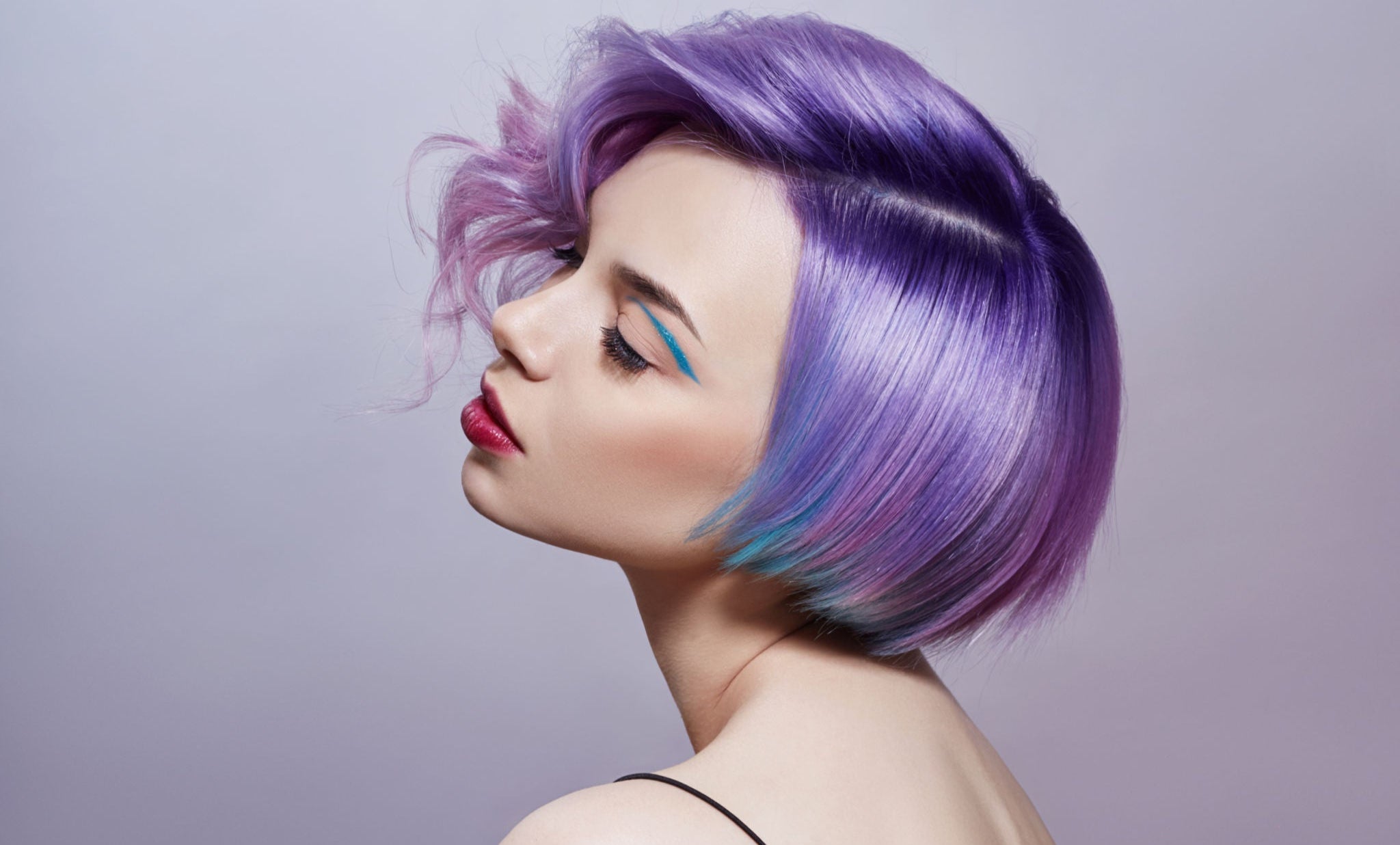 A person with a stylish purple bob hairstyle highlights soft lavender and teal tones against a light background.